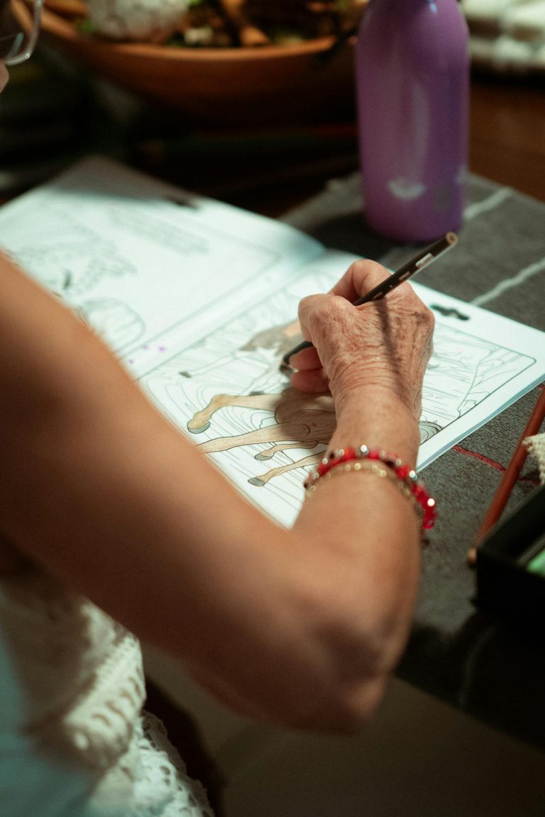 Elderly woman coloring in a book, showcasing relaxation and creativity.