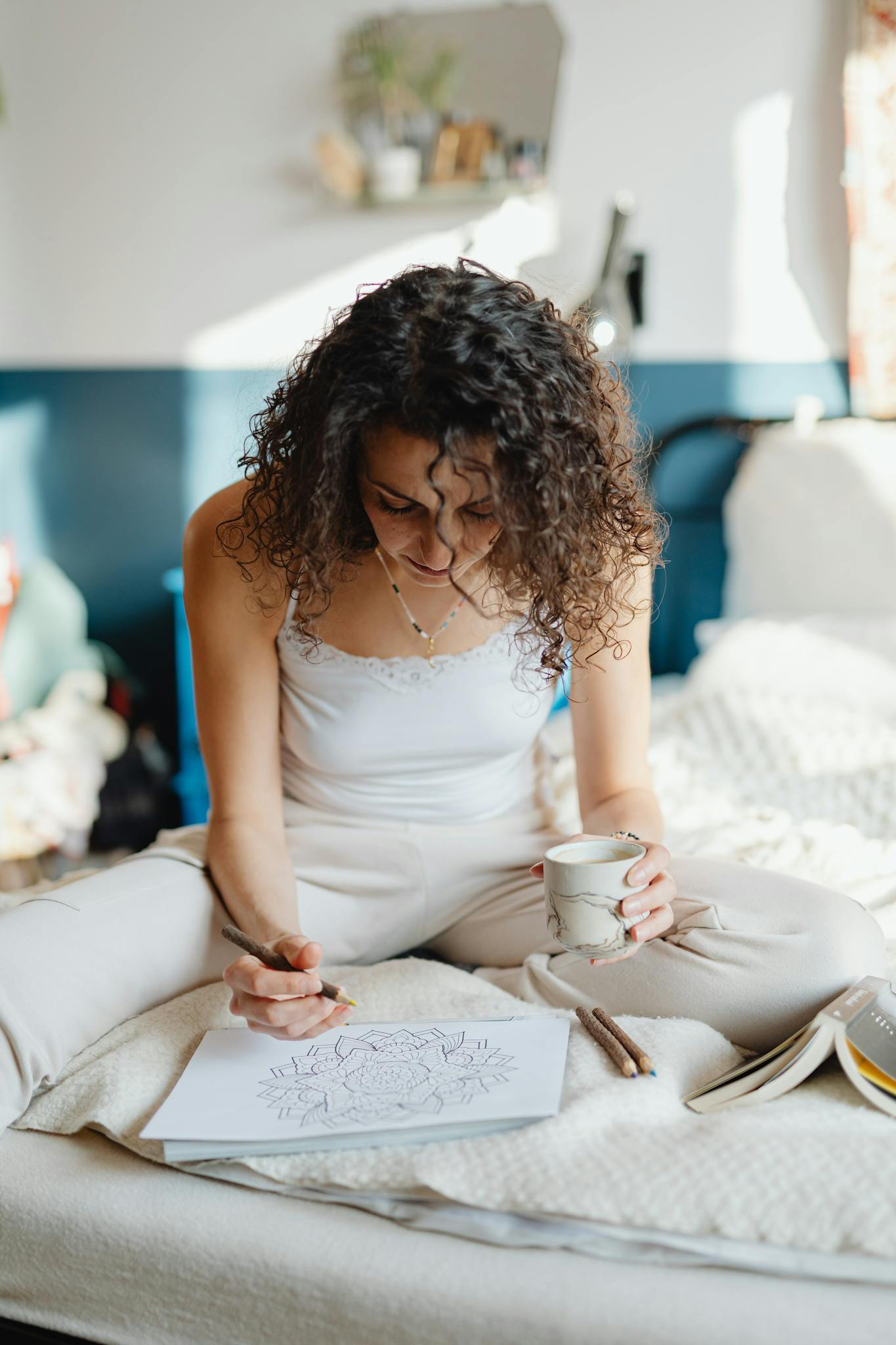 Woman enjoying a relaxing morning coloring and sipping coffee in bed.